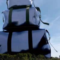 Rains Giant Blue Duffle Bags Stack Beside Eiffel Tower