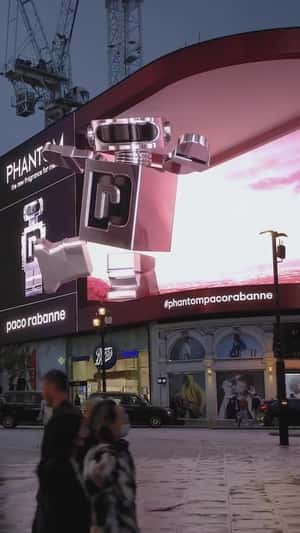 Robot Balances on Screen Edge in a 3D Billboard ad of Rabanne 