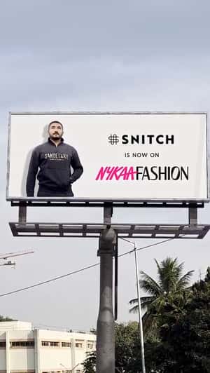 Man Crossing Through Billboards in a fake-out-of-home ad of Nykaa Fashion
