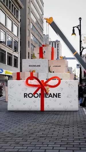Crane Truck Unwrapps Gift Box in a fake-out-of-home ad of Room Lane