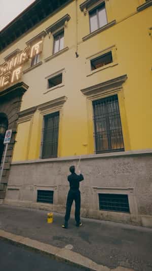 Man Paints the Building Yellow in a fake-out-of-home-ad of Onitsuka Tiger