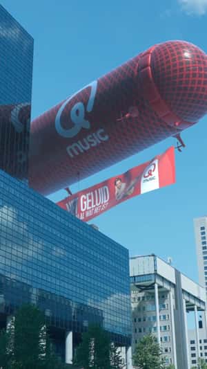 Microphone Airship Flies Above Building in a fake-out-of-home ad of Qmusic