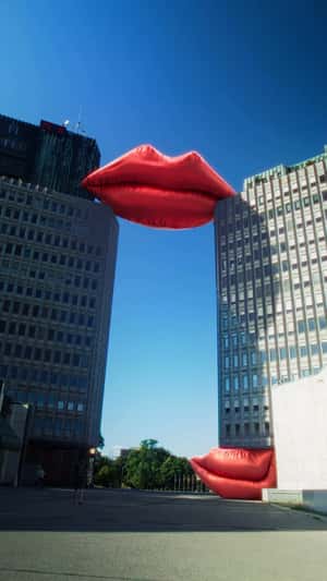 Inflatable Red Lips Rest on Two Buildings in a fake-out-of-home ad of Smile