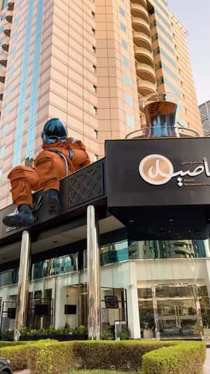 Astronaut Sitting on Cafe in a fake-out-of-home ad of Aseel Restaurant