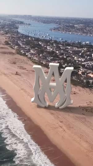 Giant Logo at Beach in fake-out-of-home ad of AMIRI
