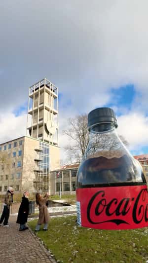 Plastic Bottle Emerges from the Ground in a fake-out-of-home ad of Coca-Cola