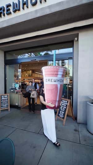 Woman Carries Smoothie Cup in a fake-out-of-home ad of Erewhon
