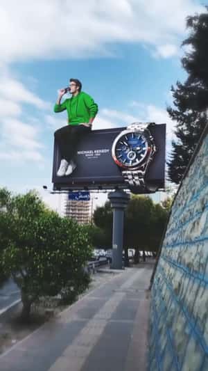 Man Poses on Watch Billboard in a fake-out-of-home ad of Michael Kennedy