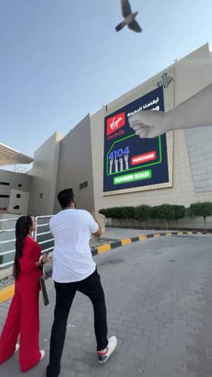 Hand Reveals QR Code on Billboard in a fake-out-of-home ad of Virgin Mobile