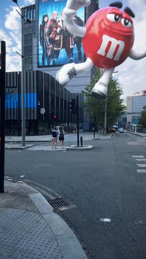 Red Character Balloon on Building in a fake-out-of-home ad of M&M's