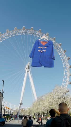 Giant Blue Duffel Coat Hangs from London Eye in a fake-out-of-home ad of Paddington the Musical