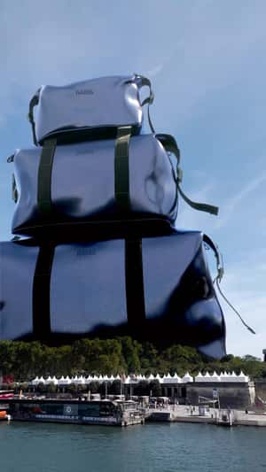 Giant Blue Duffle Bags Stack Beside Eiffel Tower in a fake-out-of-home ad of Rains