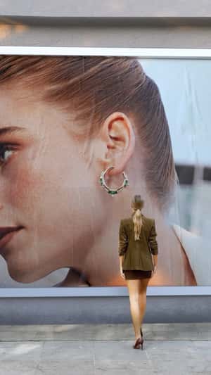Woman Takes Giant Earring From Billboard in a fake-out-of-home ad of Reis