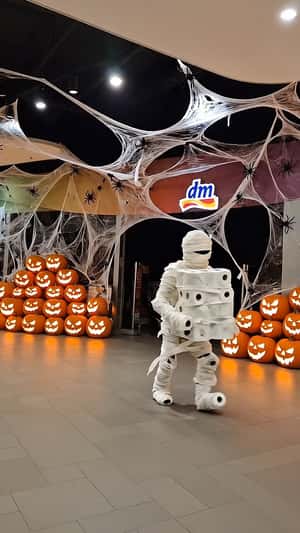 Mummy Walks Away with Stacks of Toilet Paper in a fake-out-of-home ad of DM