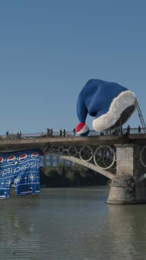 Giant Blue Santa Hat on Triana Bridge in a fake-out-of-home ad of Pepsi