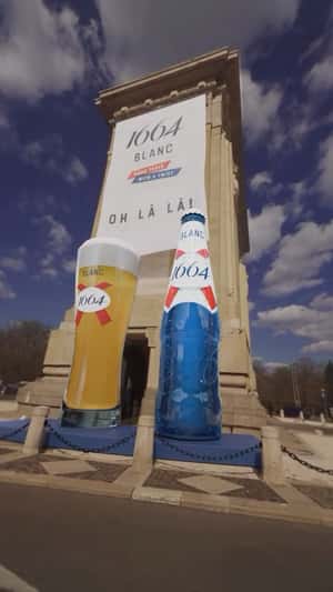Giant Beer Bottle Reveal at Arcul de Triumf in a fake-out-of-home ad of 1664 Blanc
