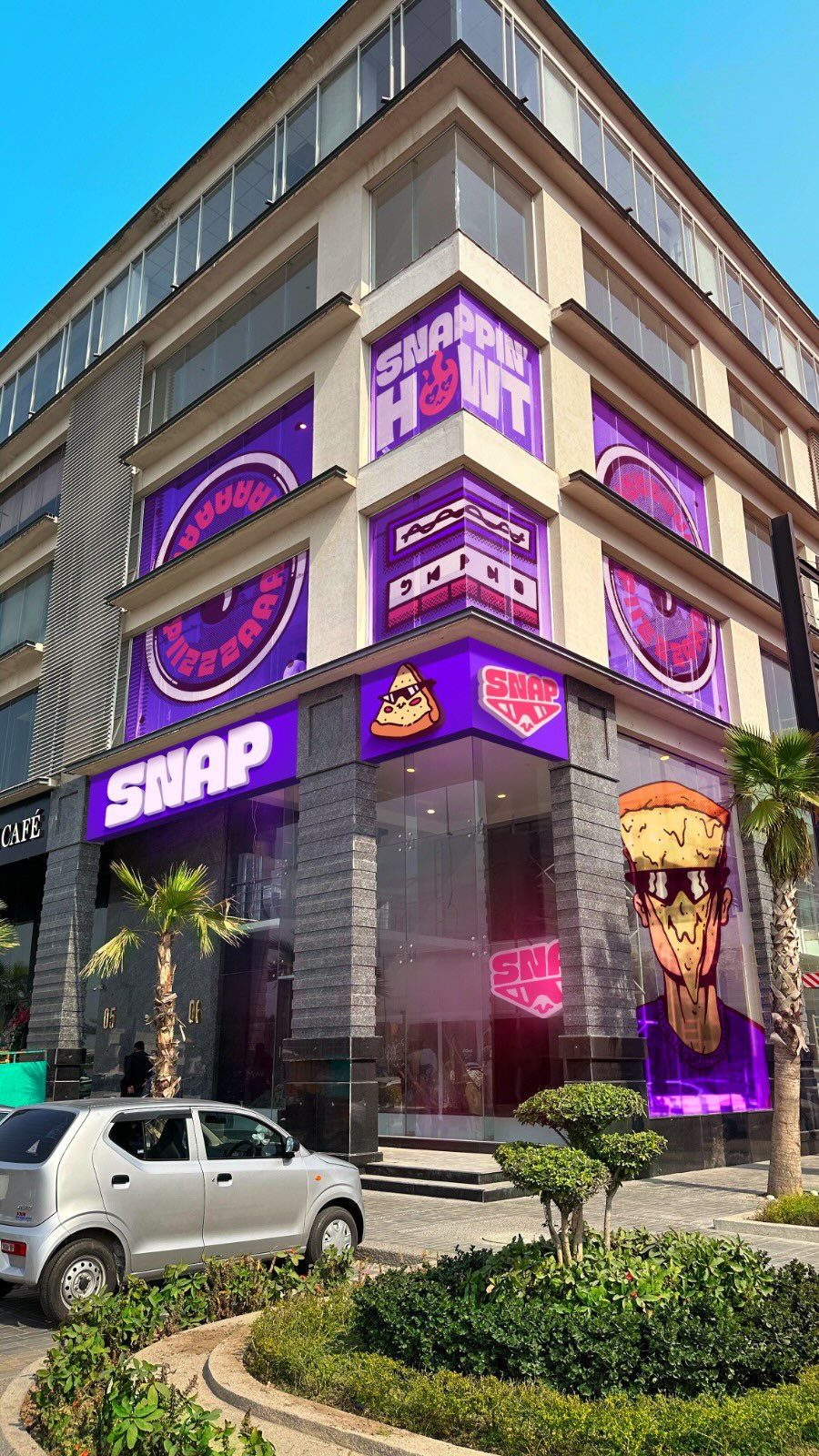 Giant Pizza Character Pops Up Behind Building in a fake-out-of-home ad of SNAP
