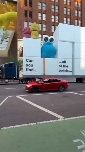 Giant Arms Play Puzzle Blocks on Facade in a fake-out-of-home ad of Board