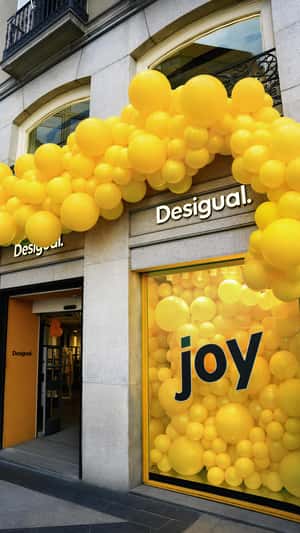 Yellow Balloons Overflow From Store in a fake-out-of-home ad of Desigual