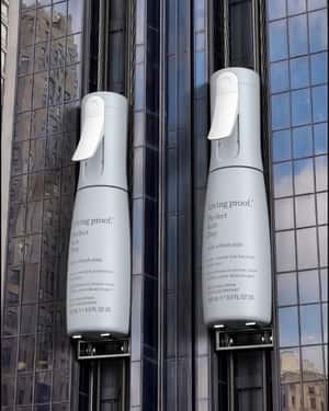 Giant Hair Mist Bottles Rise Up Building in a fake-out-of-home ad of Living Proof