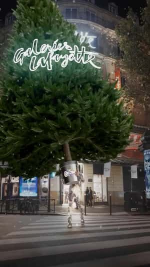 Woman Carries Christmas Tree In a fake-out-of-home ad of Galeries Lafayette