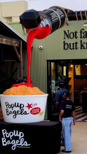 Giant Sauce Pours Over Container in a fake-out-of-home ad of PopUp Bagels