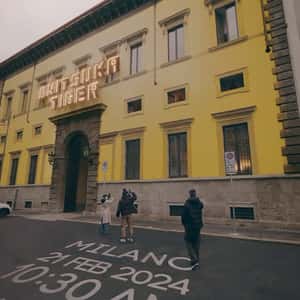Man Paints the Building Yellow in a fake-out-of-home-ad of Onitsuka Tiger