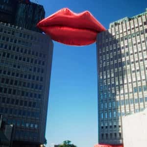 Inflatable Red Lips Rest on Two Buildings in a fake-out-of-home ad of Smile