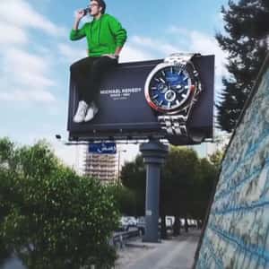 Man Poses on Watch Billboard in a fake-out-of-home ad of Michael Kennedy