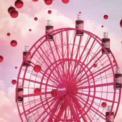 Lip Tint Wagons on Pink Ferris Wheel in a fake-out-of-home ad of Benefit Cosmetics