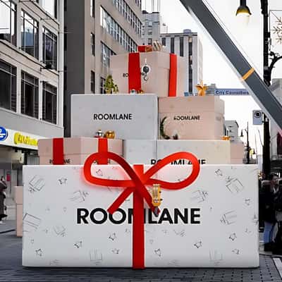 Crane Truck Unwrapps Gift Box in a fake-out-of-home ad of Room Lane