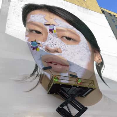 Workers Cleaning Woman’s Face on Mural in a fake-out-of-home ad of Benefit