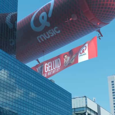 Microphone Airship Flies Above Building in a fake-out-of-home ad of Qmusic