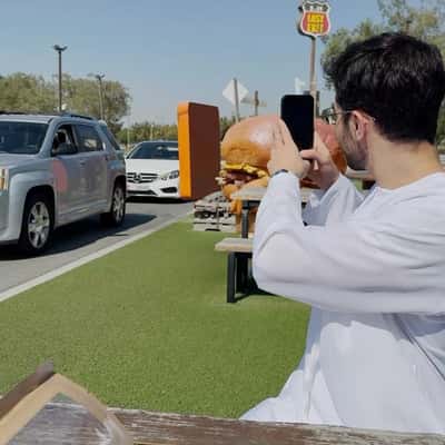 Burger Mascot Approaches Car in a fake-out-of-home-ad of Last Exit Dubai